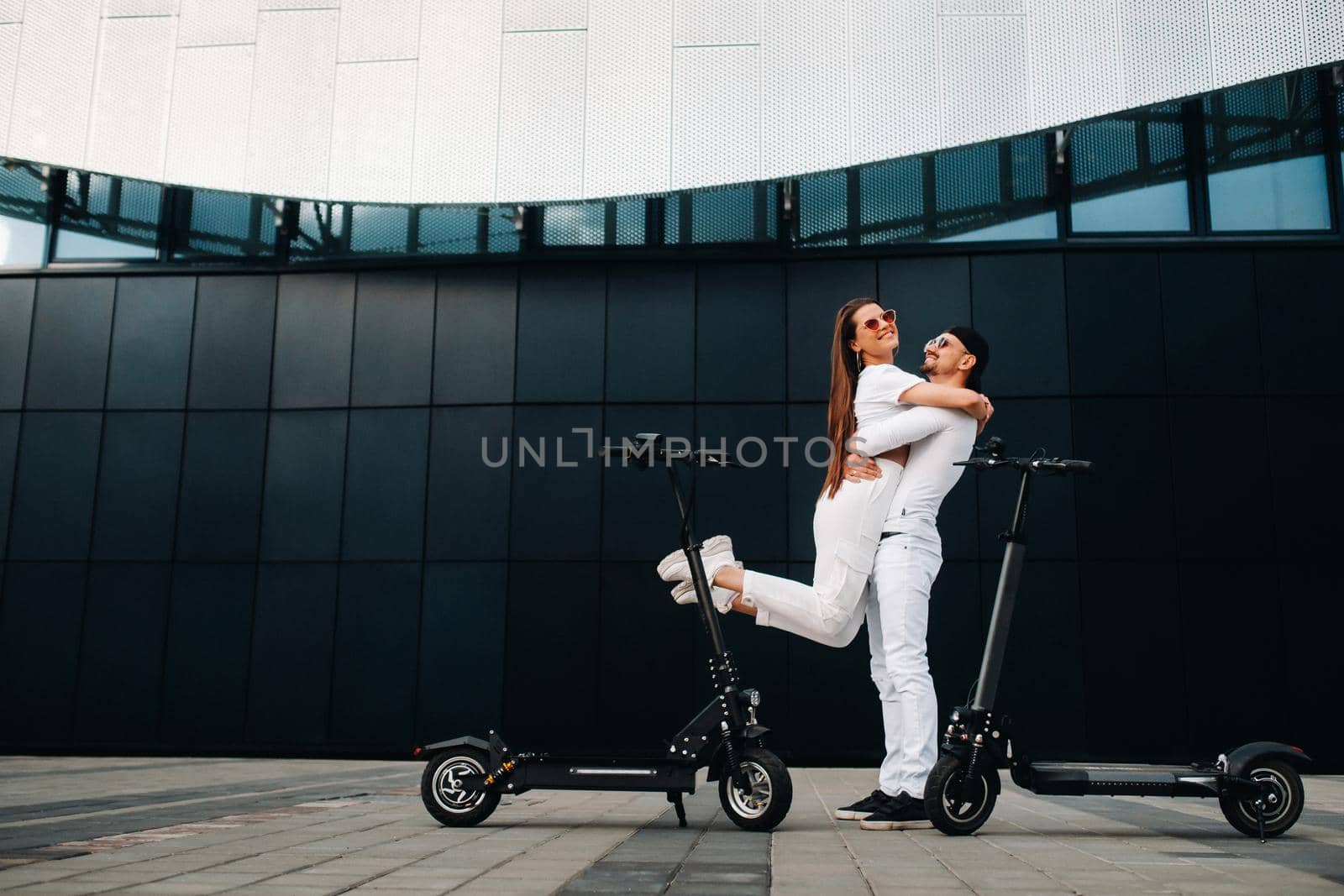 A girl and a guy are walking on electric scooters around the city, a couple in love on scooters