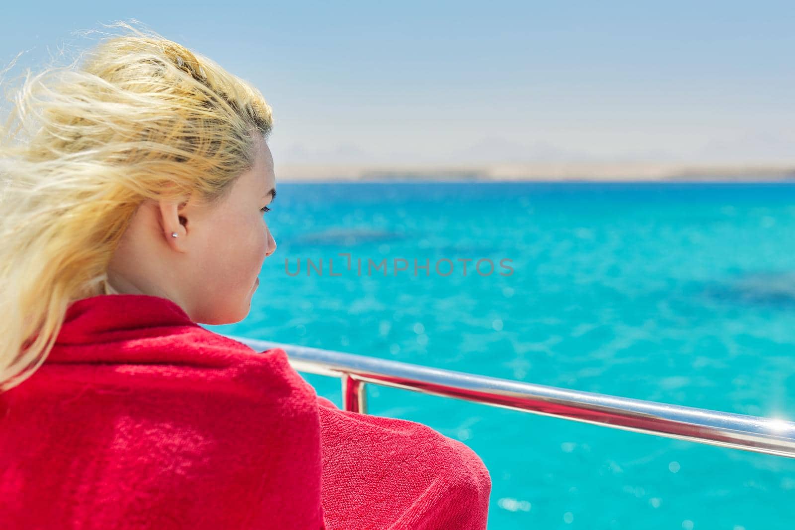 Young blonde female on yacht looking at turquoise coral reefs in Red Sea. Tourism, nature, travel, diving, snorkeling, water world concept, copy space