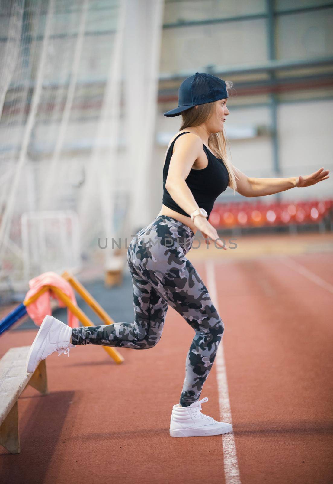 Young athletic woman in leggings warming up using a bench. Mid shot