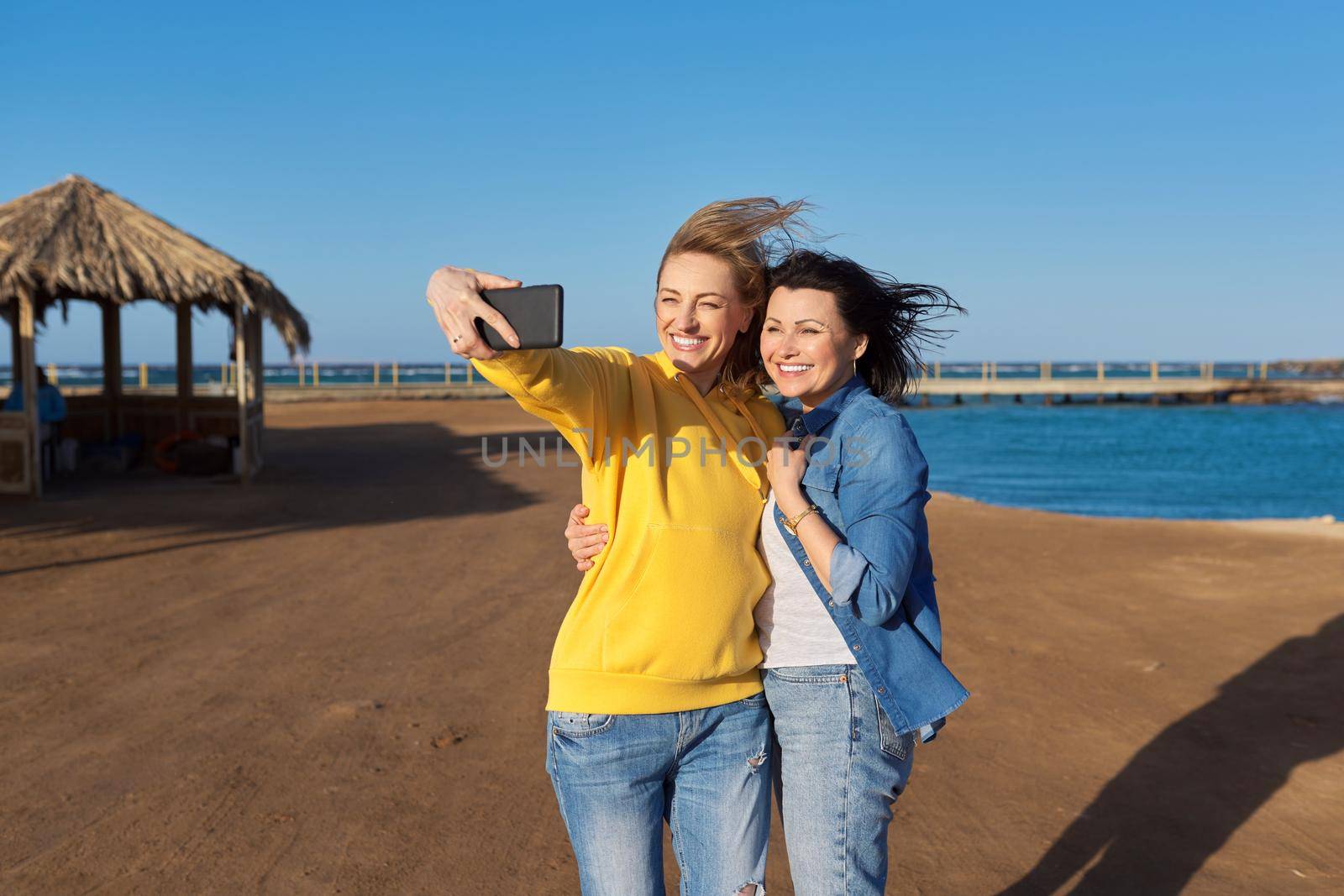 Two mature happy women taking selfie photo together using smartphone by VH-studio