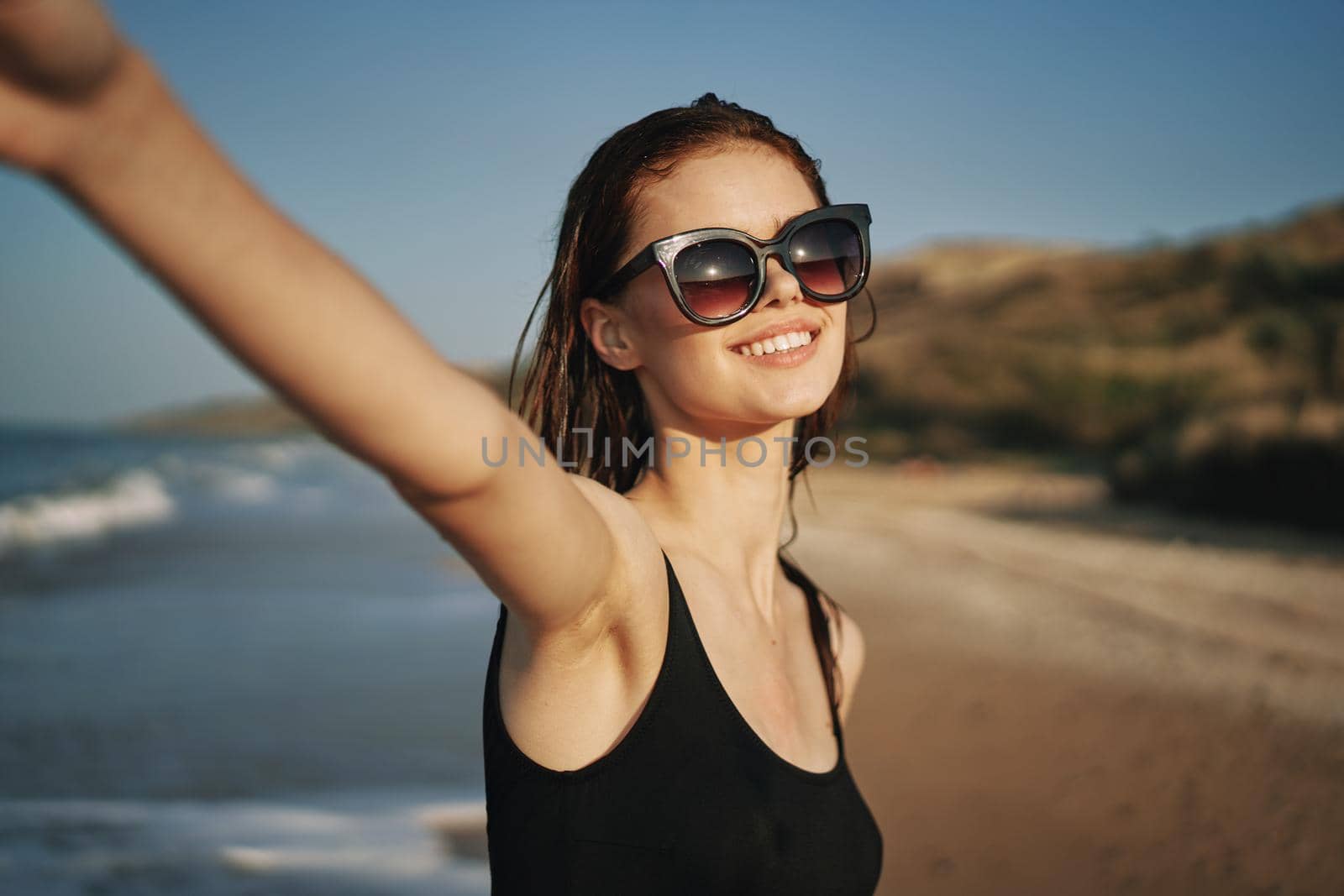 cheerful woman in a black swimsuit walking along the beach tropics summer. High quality photo