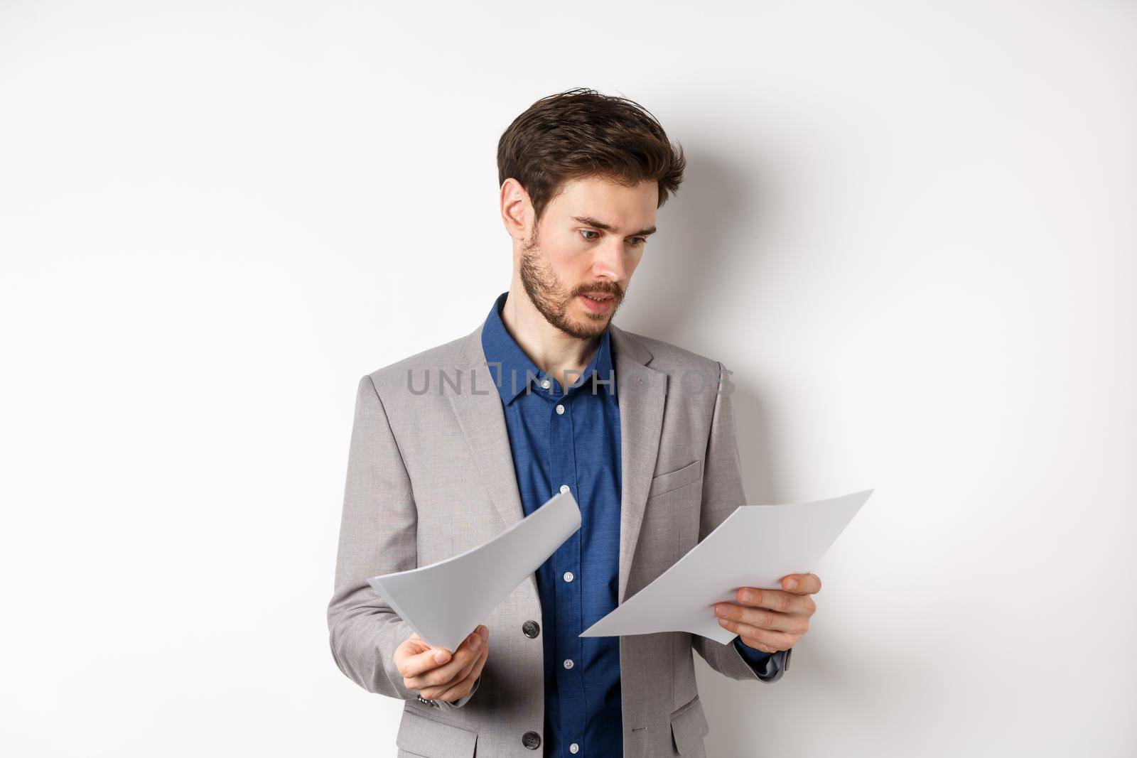 Businessman in suit looking through papers, reading documents at work, standing busy on white background.