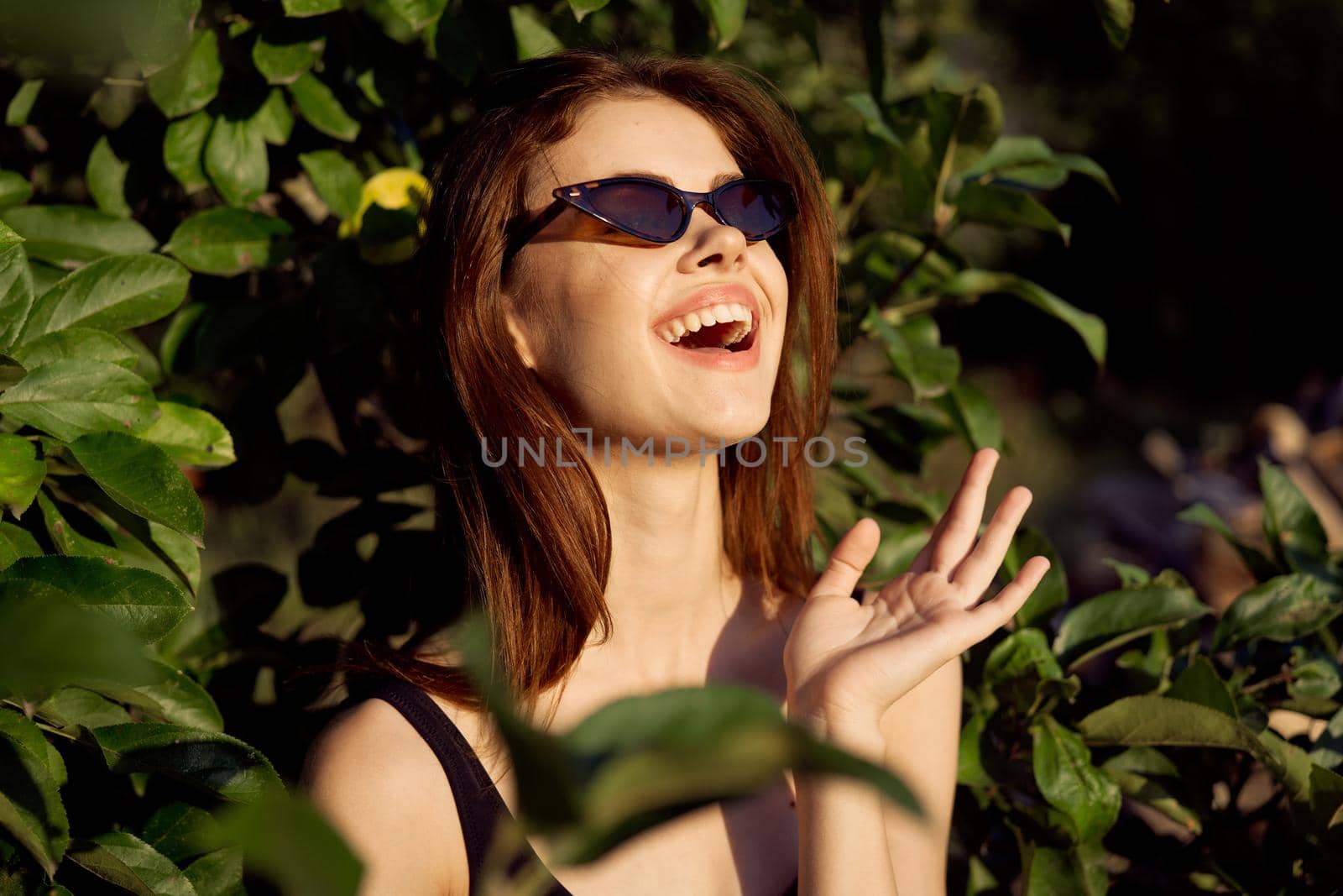 pretty woman wearing sunglasses green leaves posing summer. High quality photo