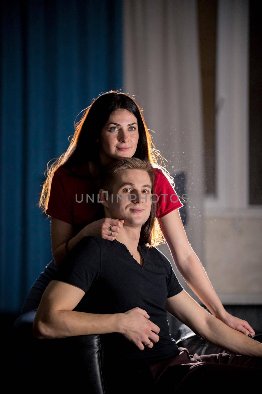 Young pretty couple sitting on a couch. Mid shot