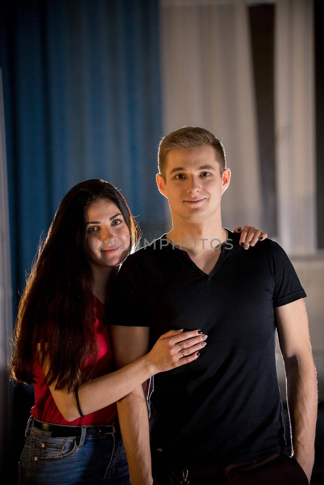 Young smiling couple. A young woman hugging her boyfriend from the back. Mid shot