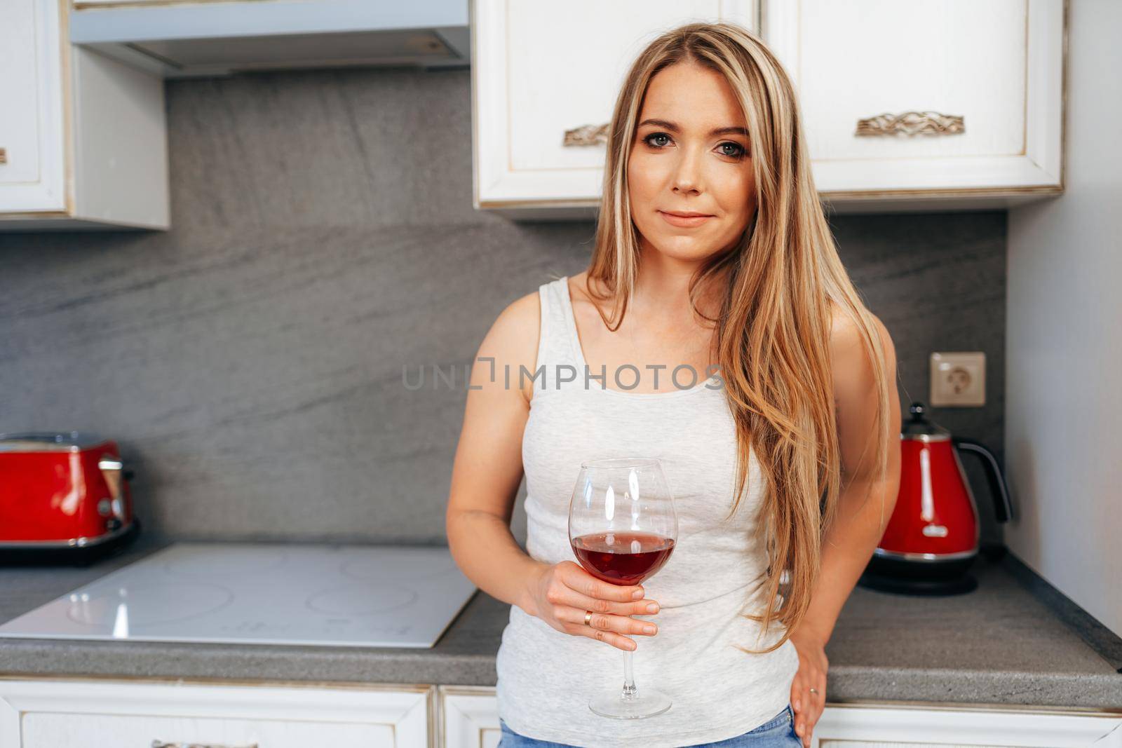 Attractive young woman relaxing with wineglass at her kitchen at home