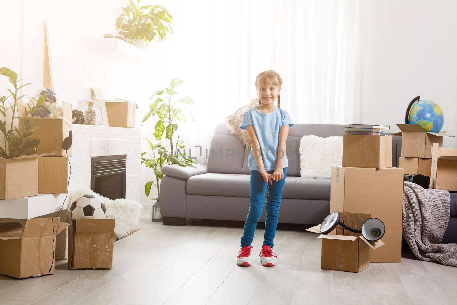 Little girl moving into new house, near cardboard box.