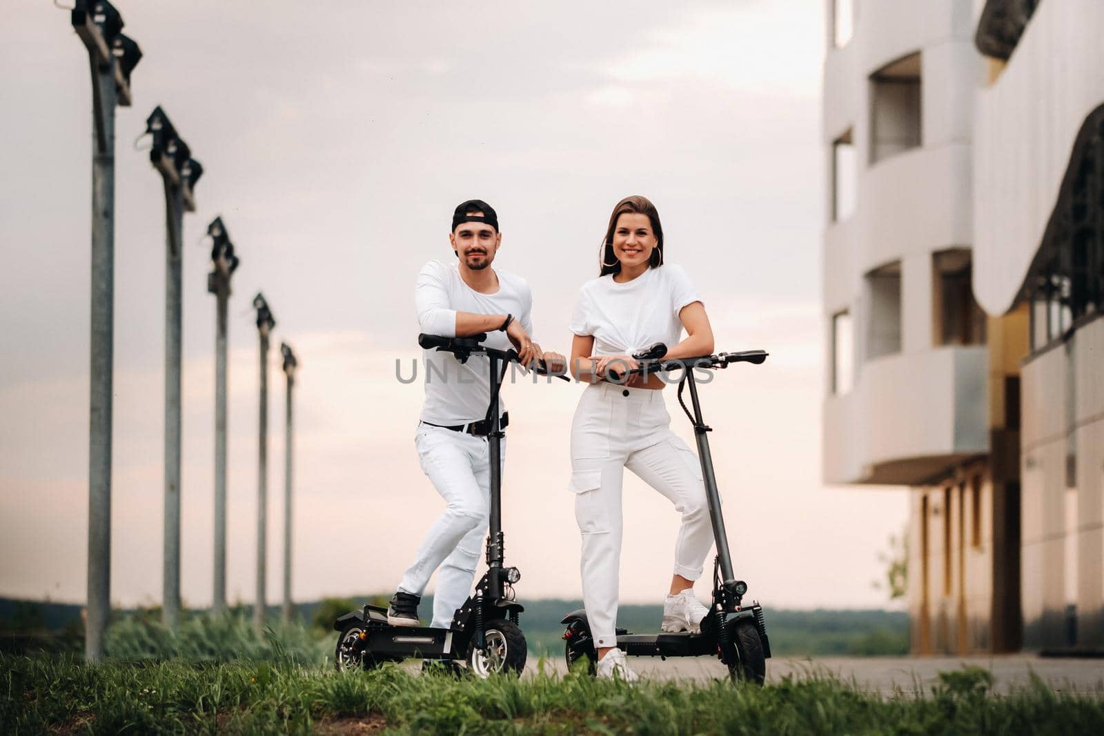 A girl and a guy are walking on electric scooters around the city, a couple in love on scooters