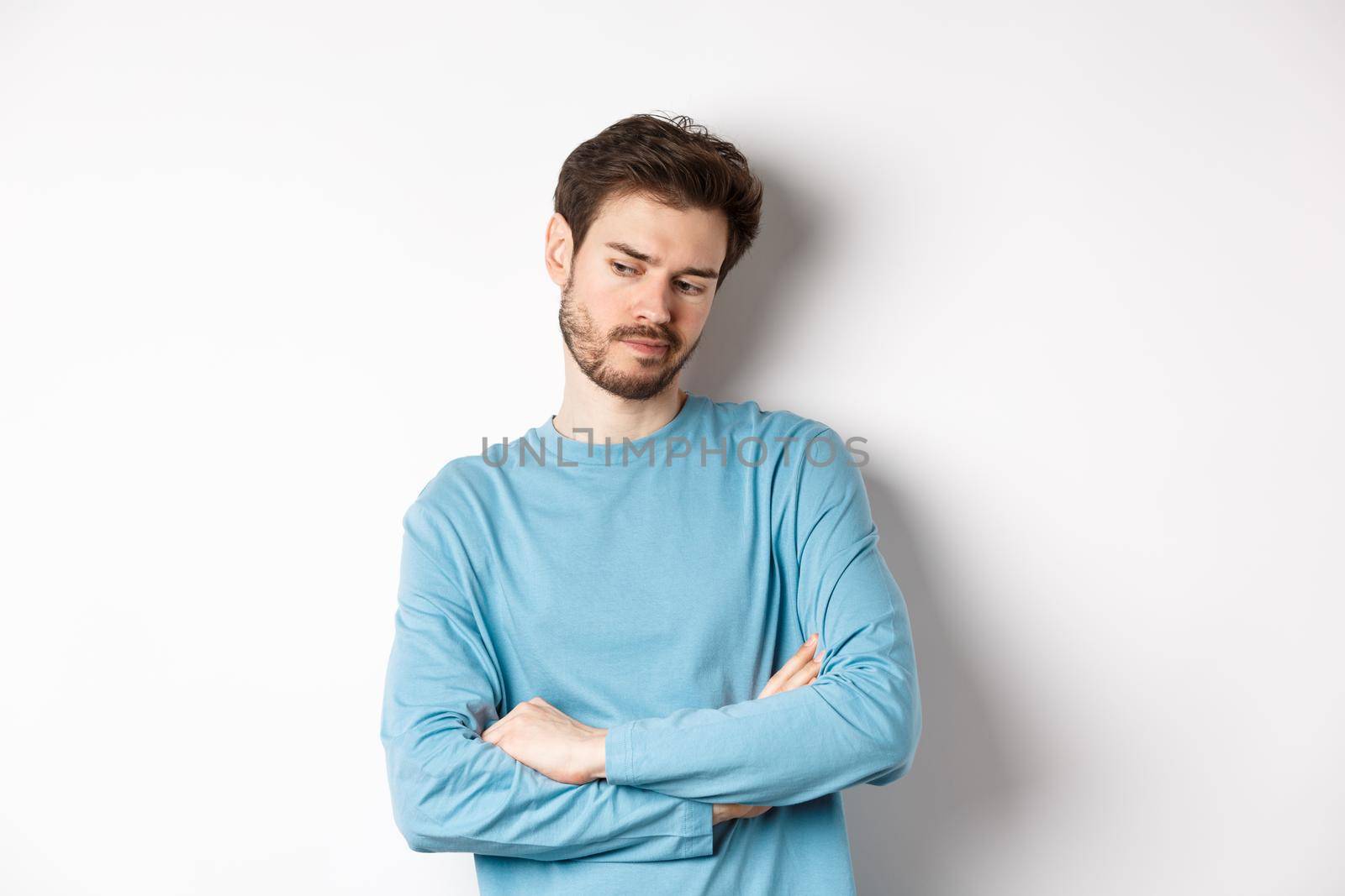Indecisive and thoughtful bearded man thinking, looking down pensive and making choice, standing over white background.