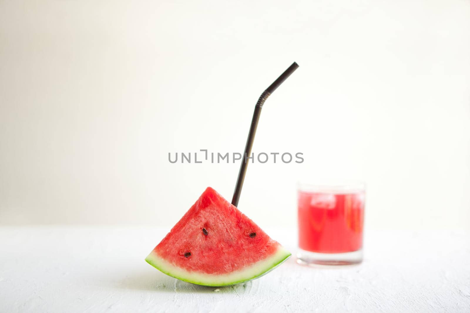 watermelon slice with straw and juice on the white board. Delicious drink - vegetarian cocktail from fresh fruit with ice. conceptual image