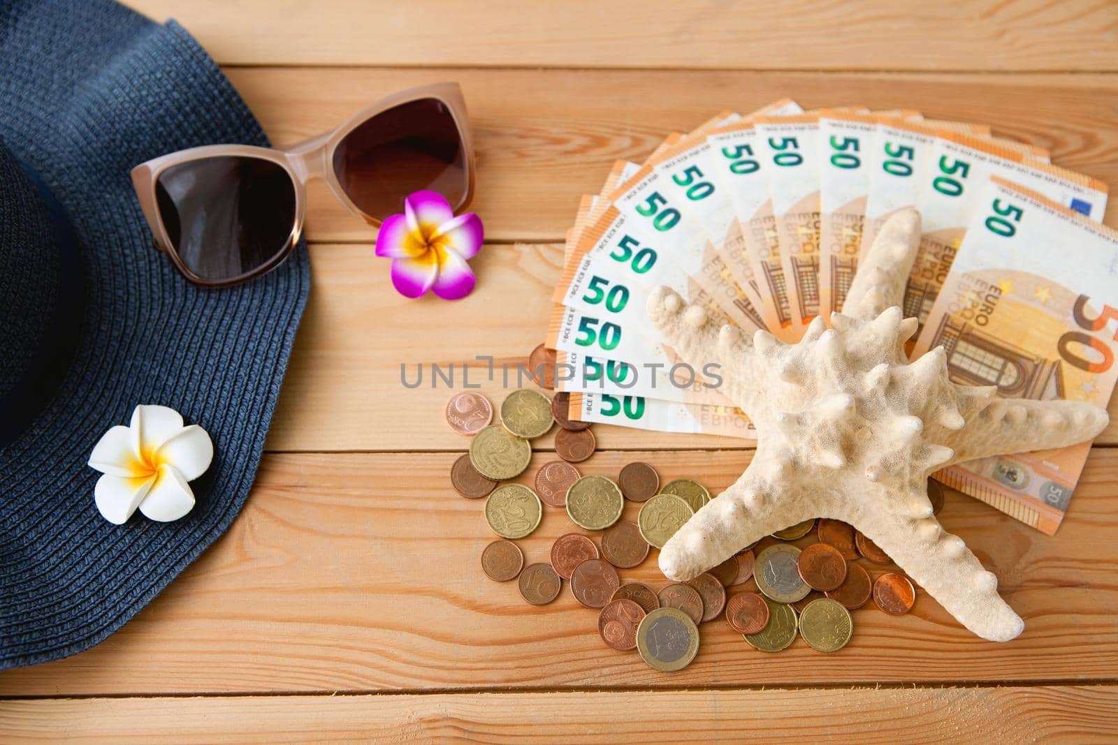 Accessories for summer holiday in Europe, on a wooden background - eruro money, seastar, sunglasses and hat with flowers