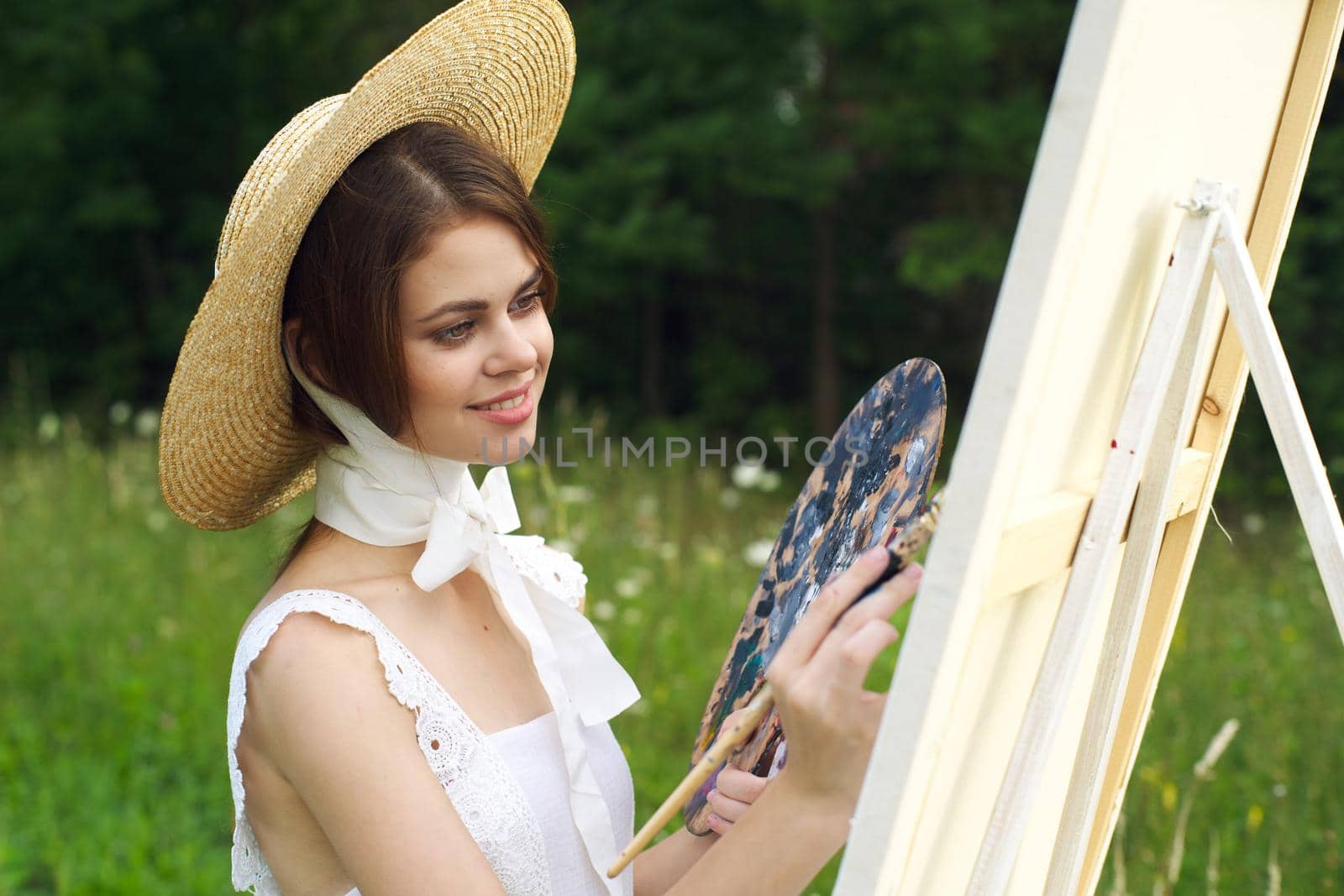 Woman in white dress outdoors artist drawing easel. High quality photo