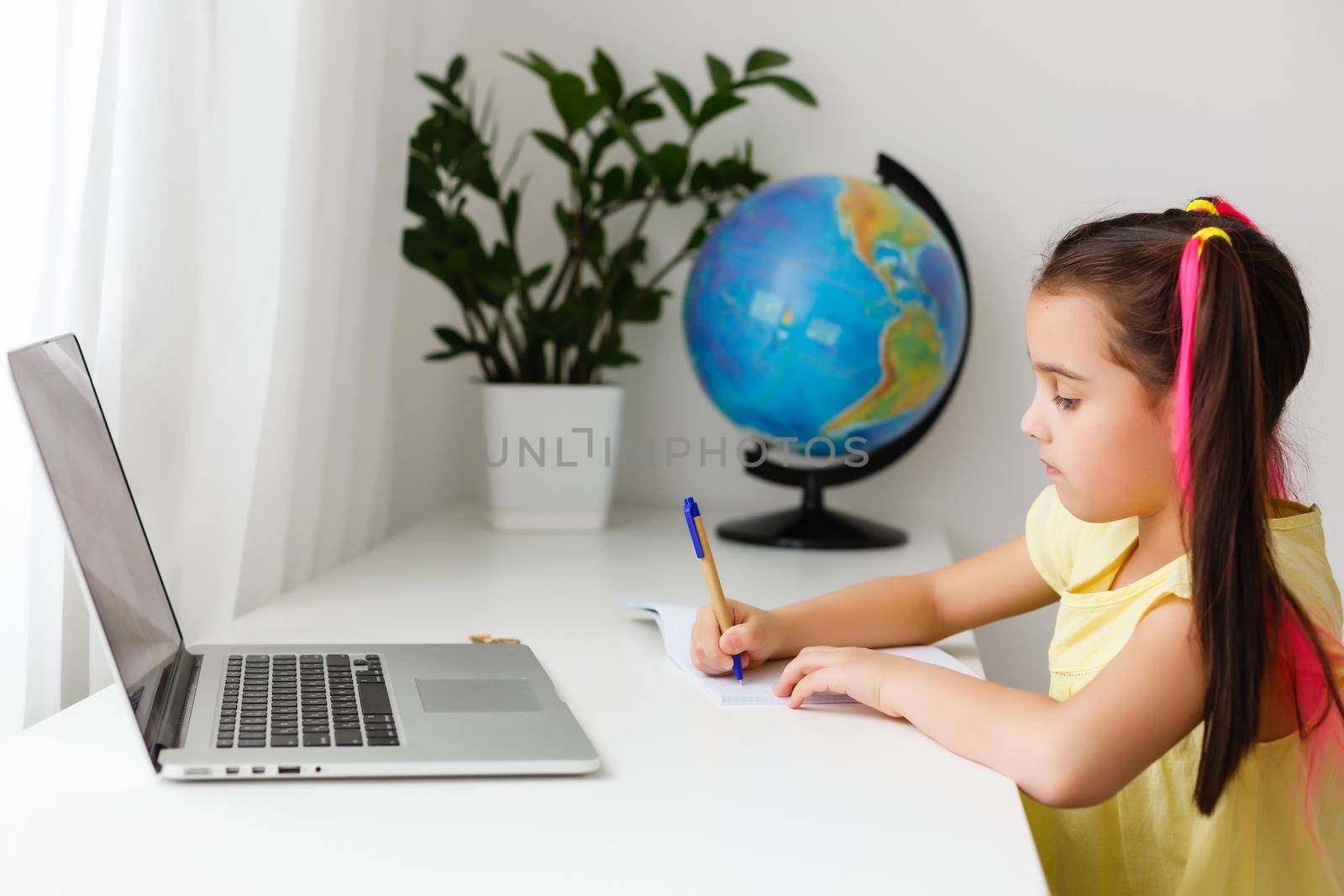 Cool online school. Kid studying online at home using a laptop. Cheerful young little girl using laptop computer studying through online e-learning system. Distance or remote learning by Andelov13