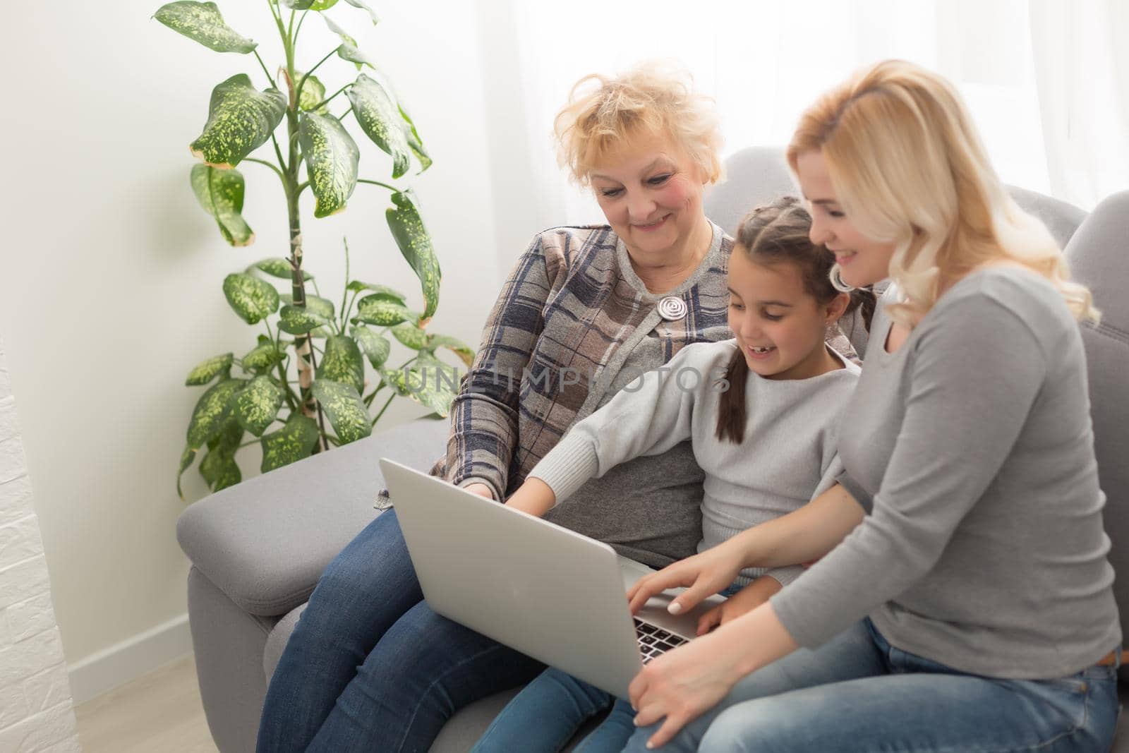 Grandmother and daughter teaching child use laptop application, playing game by Andelov13