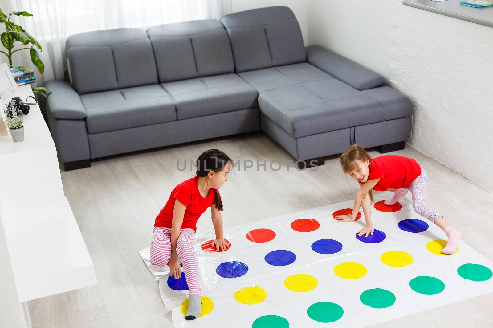 two little girls Having Fun Playing Game On Floor At Home. Siblings Friendship