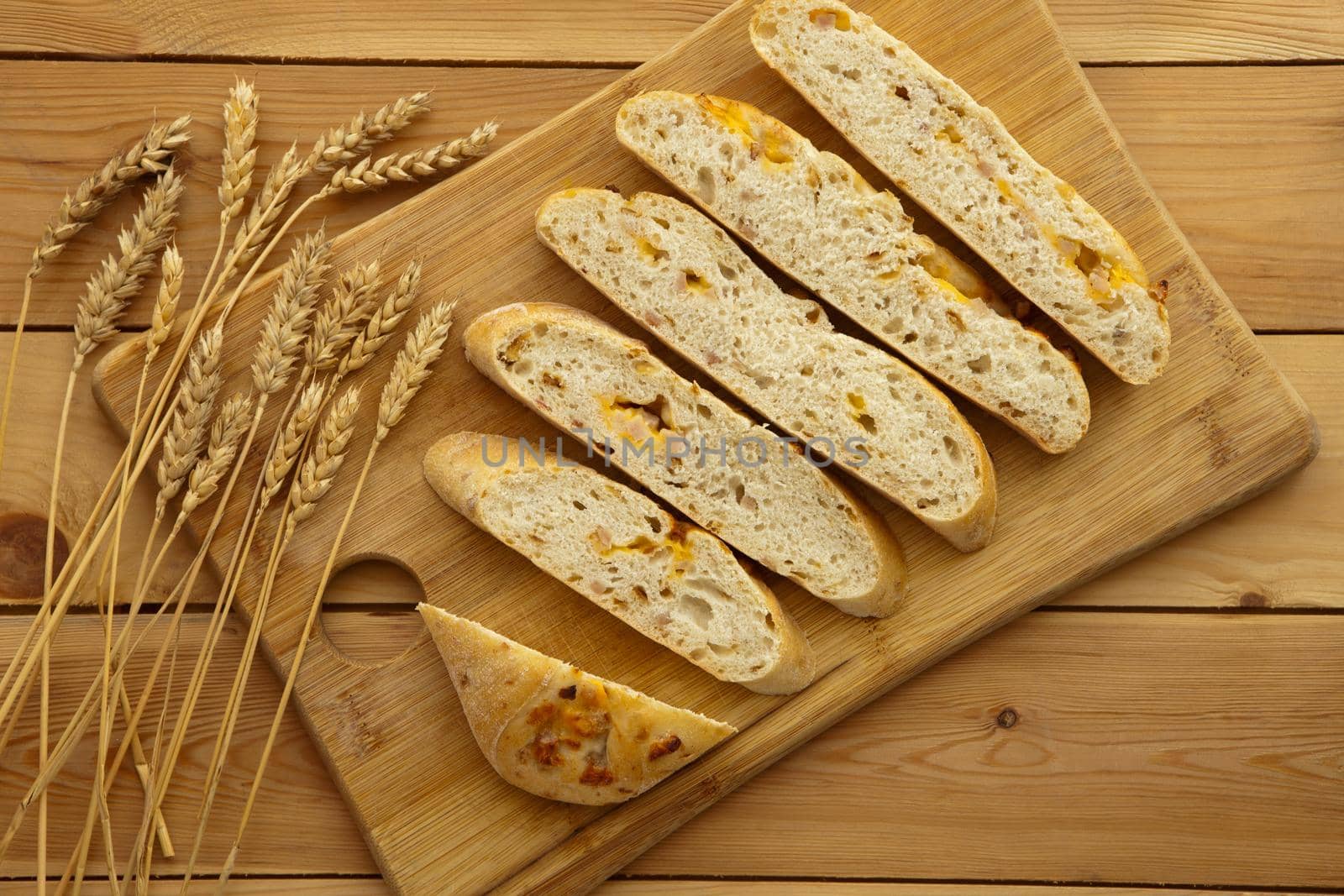 Fresh whole grain bread with cheese and ham. Natural food concept. Loaf of organic bread on wooden background.