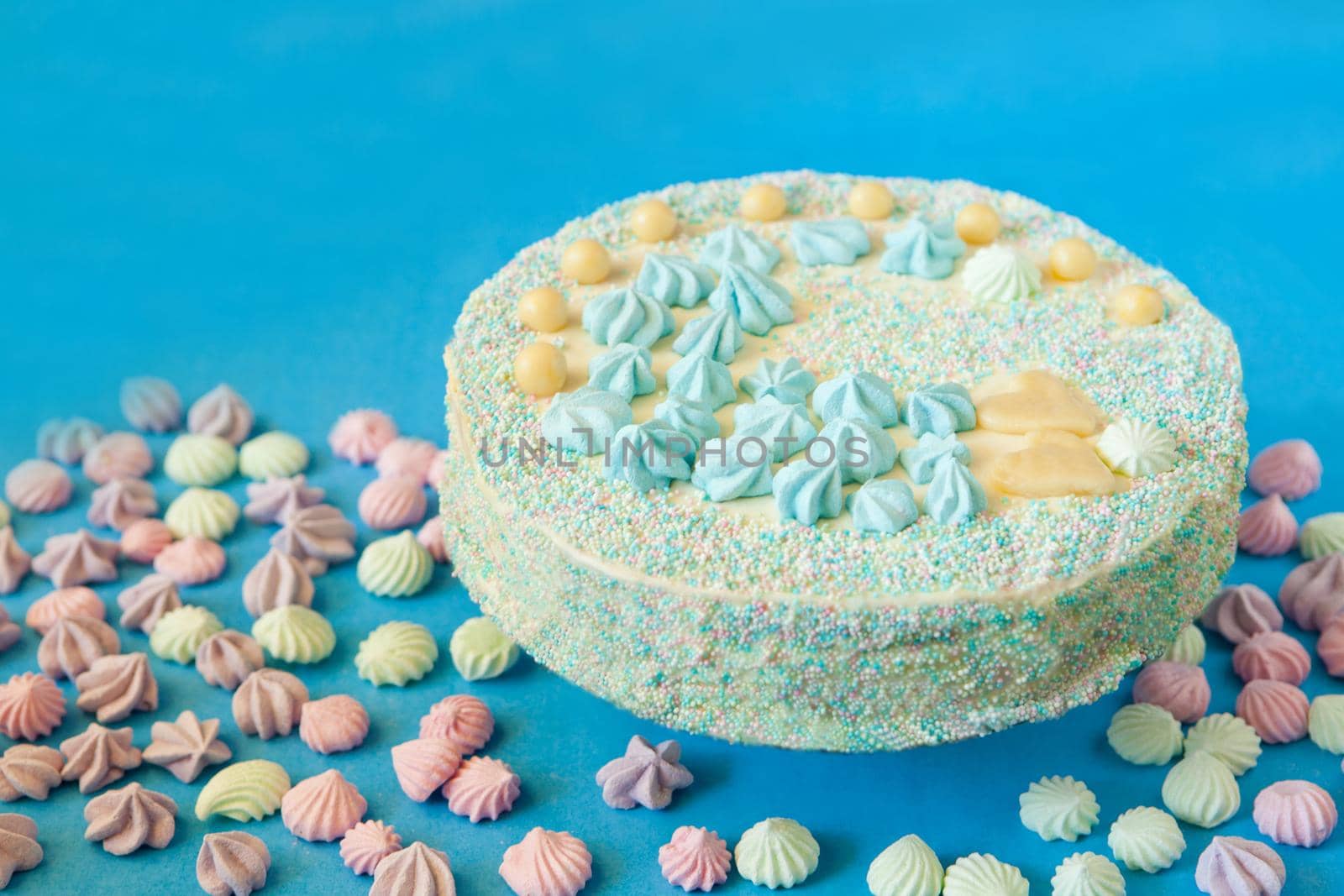 blue cake with candies for babyshower party with meringue. Homemade cake for a newborn boy On a blue background.