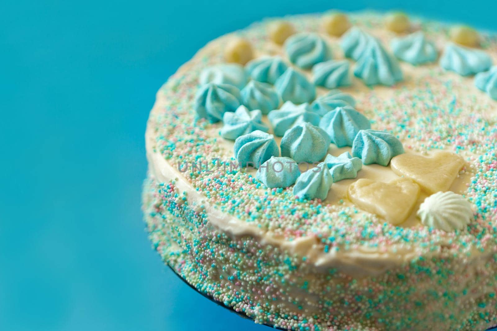blue cake with candies for babyshower party with meringue close up view. Homemade cake for a newborn boy On a blue background.