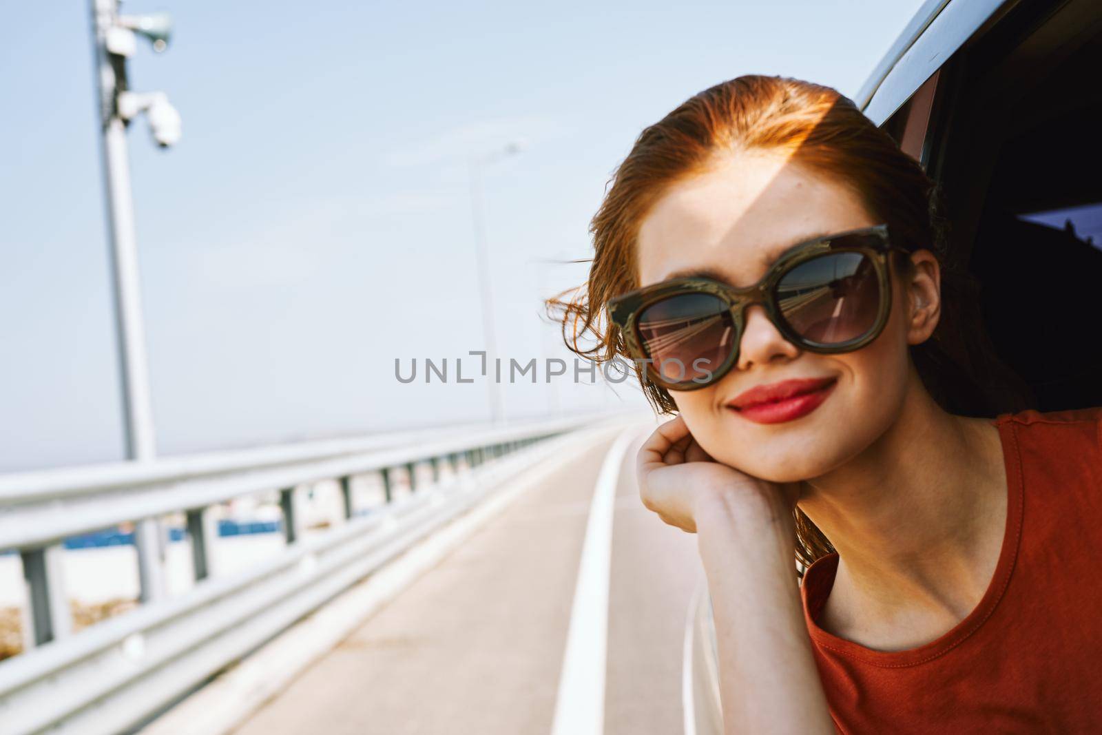 cheerful woman peeking out of the car window trip adventure lifestyle. High quality photo