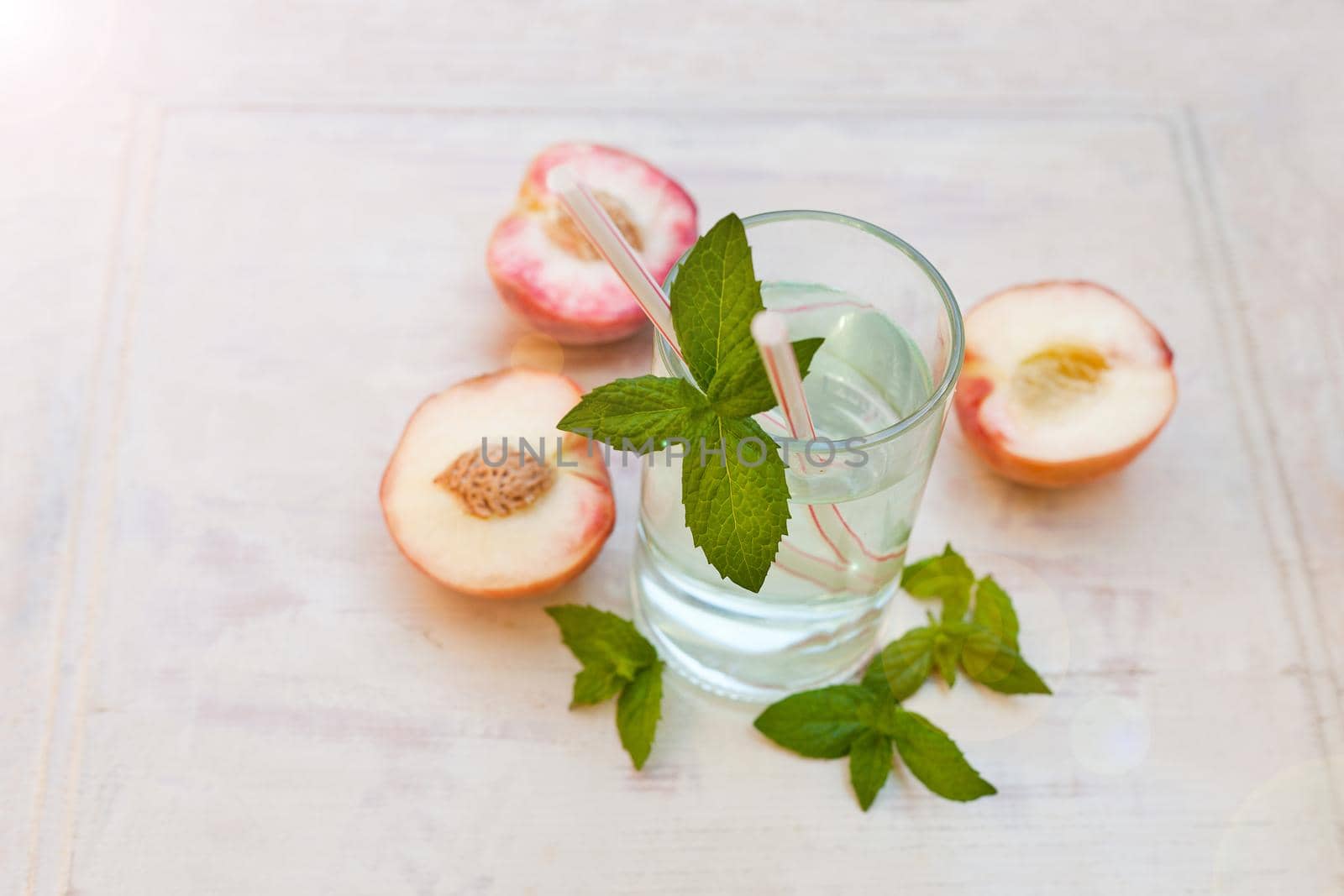 water drink with peaches - refreshing iced tea with peppermint and peaches on grey background, selective focus.