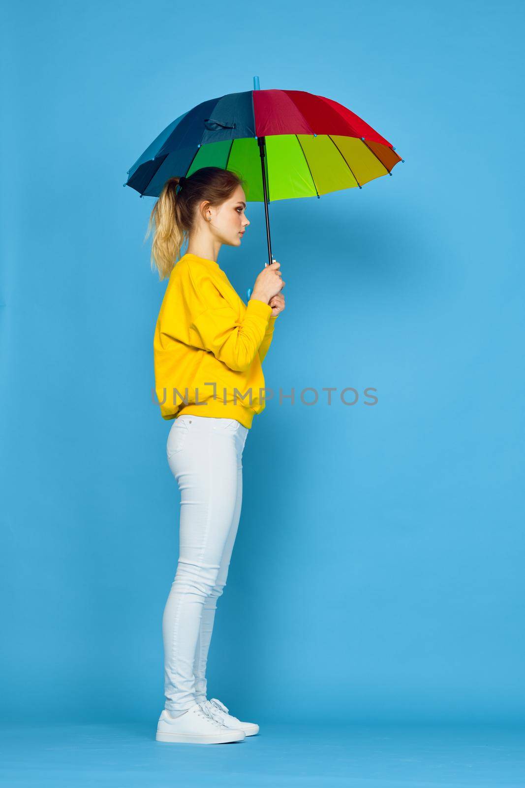 woman with multicolored umbrella in yellow sweater posing rainbow colors. High quality photo