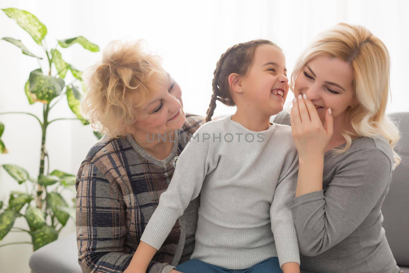 Portrait of three generations of women look at camera posing for family picture, cute little girl hug mom and granny enjoy time at home, smiling mother, daughter and grandmother spend weekend together by Andelov13