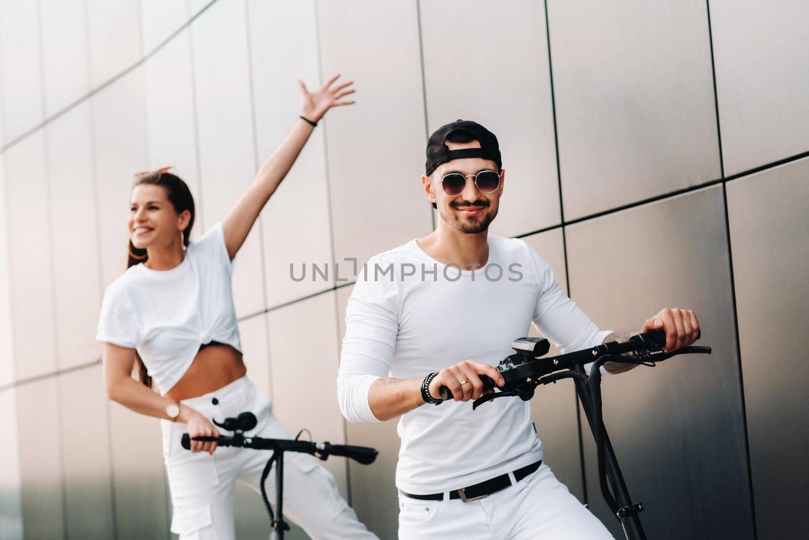 A girl and a guy are walking on electric scooters around the city, a couple in love on scooters