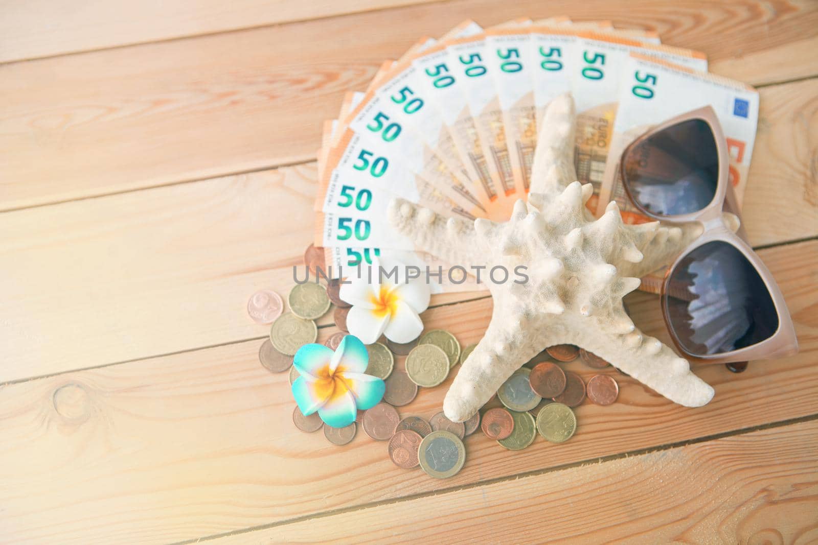 Seastar with sunglases on lot european money banknotes. Euro money and flowers on wooden backgrop as summer vacation and travel concept
