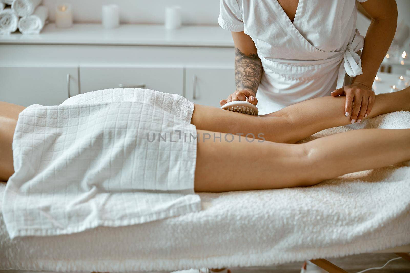 Confident female specialist is doing anticellulite leg massage to beautiful healthy caucasian female client
