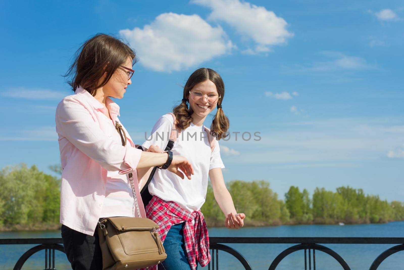 Mother and daughter teenager walk down the street, the woman looks at the clock, rushes, is late, quickly goes by VH-studio