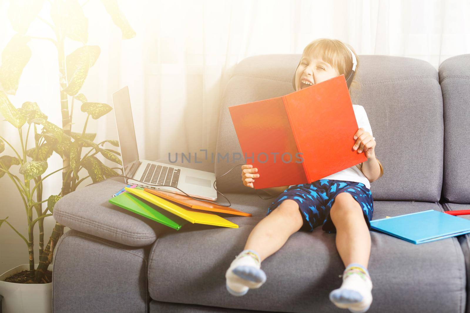 The girl at home communicates with friends on the Internet. Kids distance learning. Cute little girl using laptop at home. Education, online study, home studying, schoolgirl children lifestyle concept by Andelov13