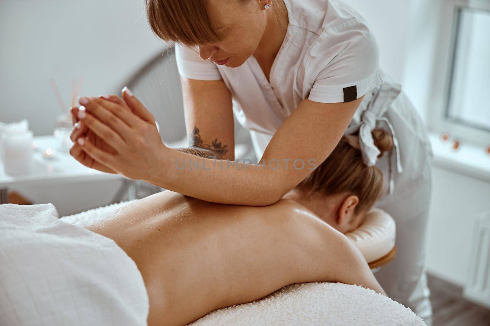 Professional confident massage master is doing procedures to caucasian woman in minimalistic modern cabinet