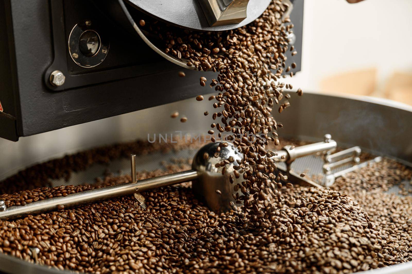 Young specialist worker is roasting coffee in hangar