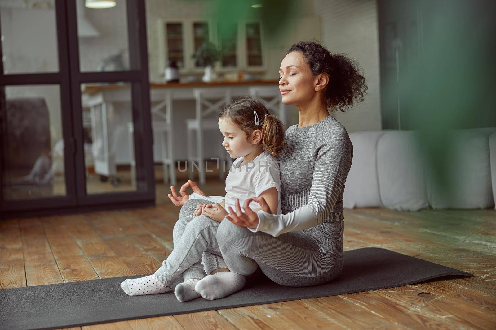 Calm mother and daughter doing yoga together by Yaroslav_astakhov