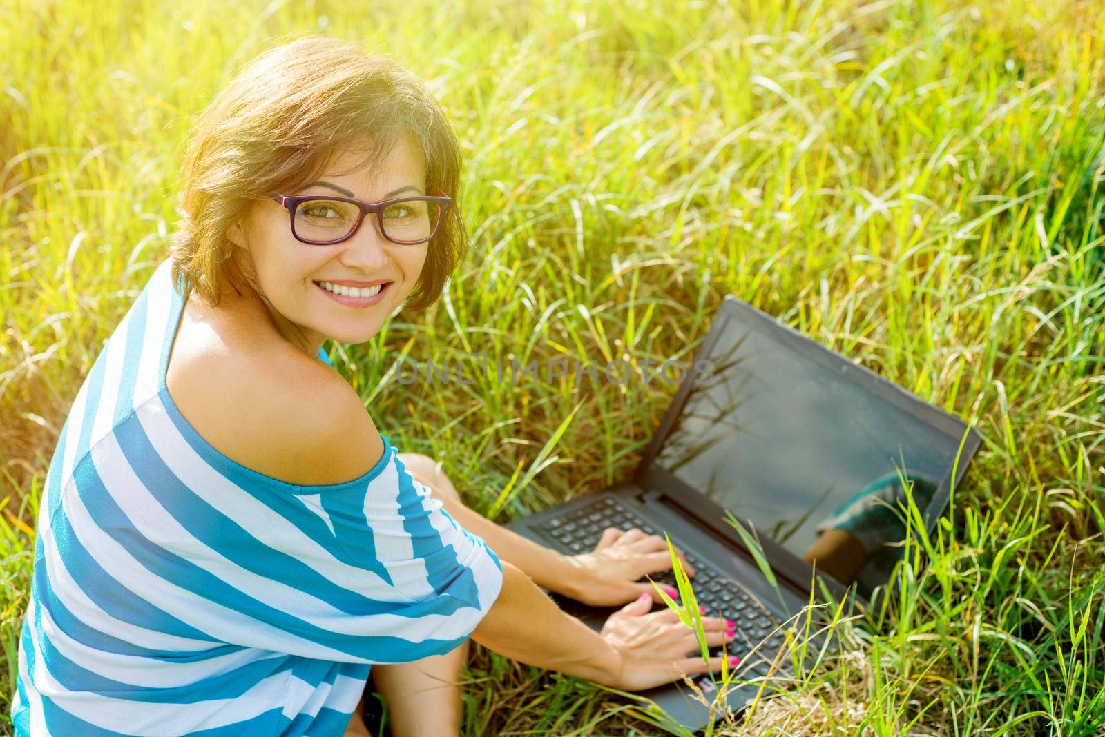 Beautiful woman with a laptop. Smiling at the camera. The picture was taken in the park.