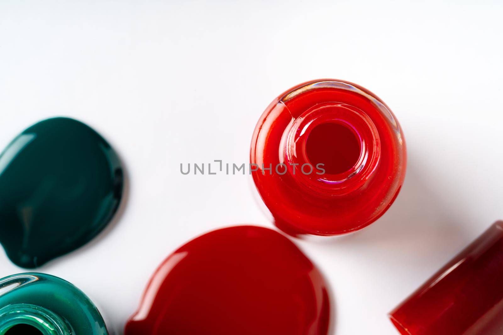 Nail polishes spilled out of bottles on white background. Close up.