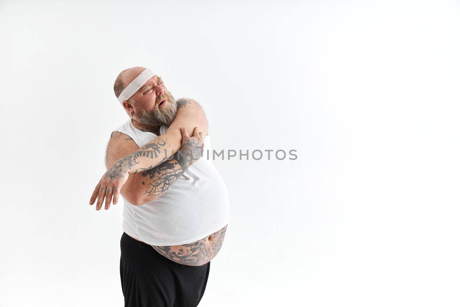 Sporty fat man with beard and tattoos is doing yoga