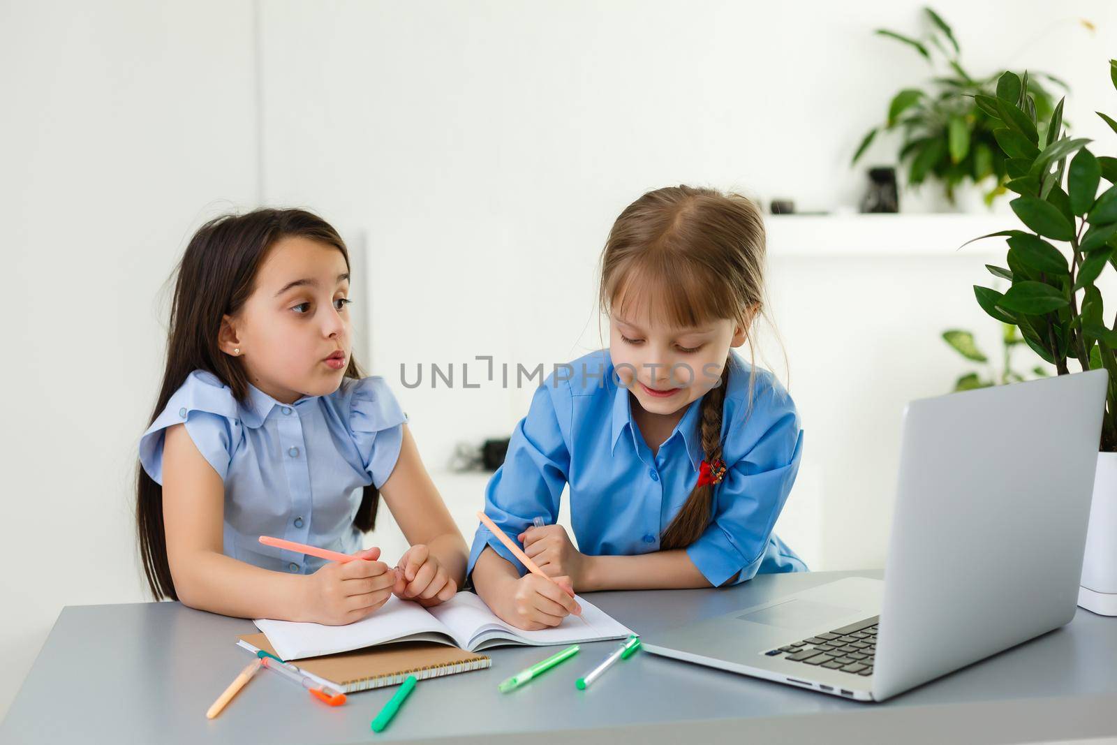 Cool online school. Kids studying online at home using a laptop. Cheerful young little girls using laptop computer studying through online e-learning system. Distance or remote learning by Andelov13