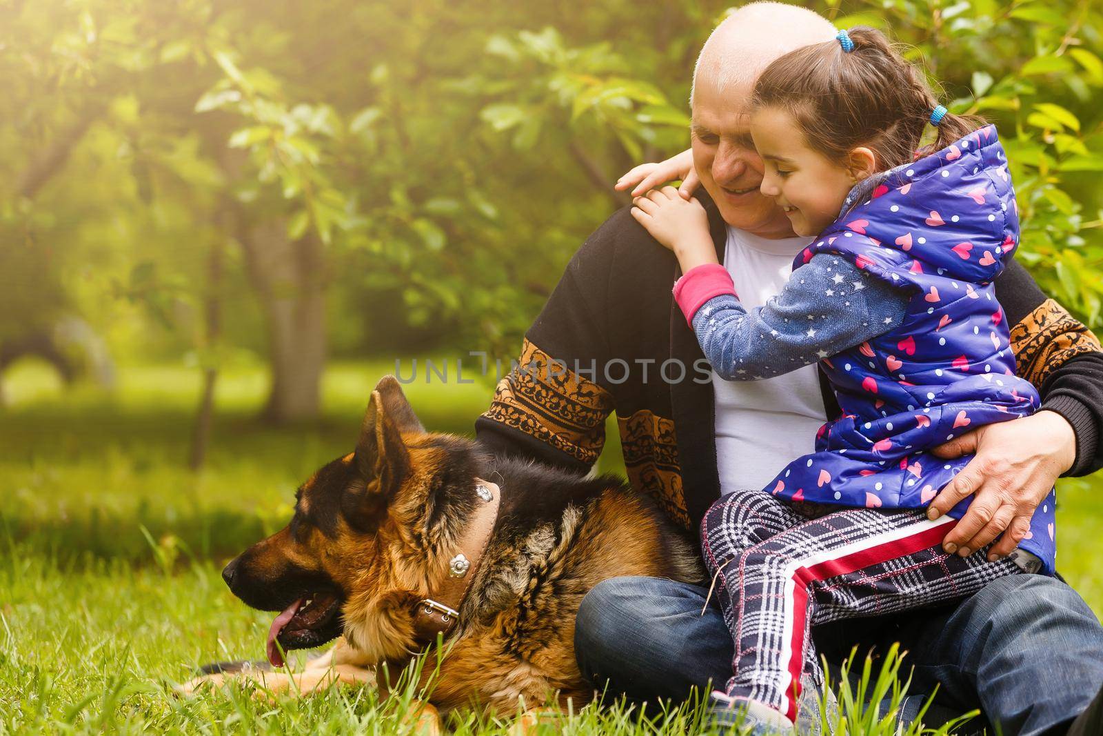 Grandfather with granddaughter and a dog in the garden