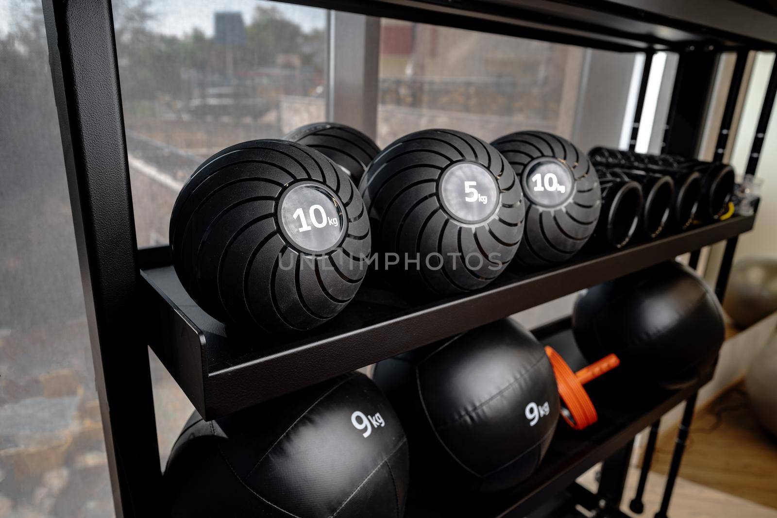 Balls and foam roller sport equipment in a gym on shelf
