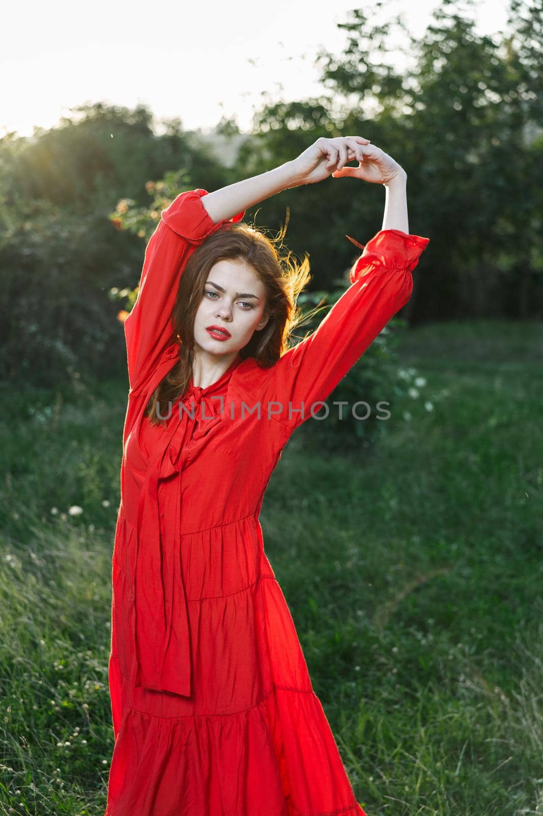 attractive woman in red dress posing in nature green grass by Vichizh