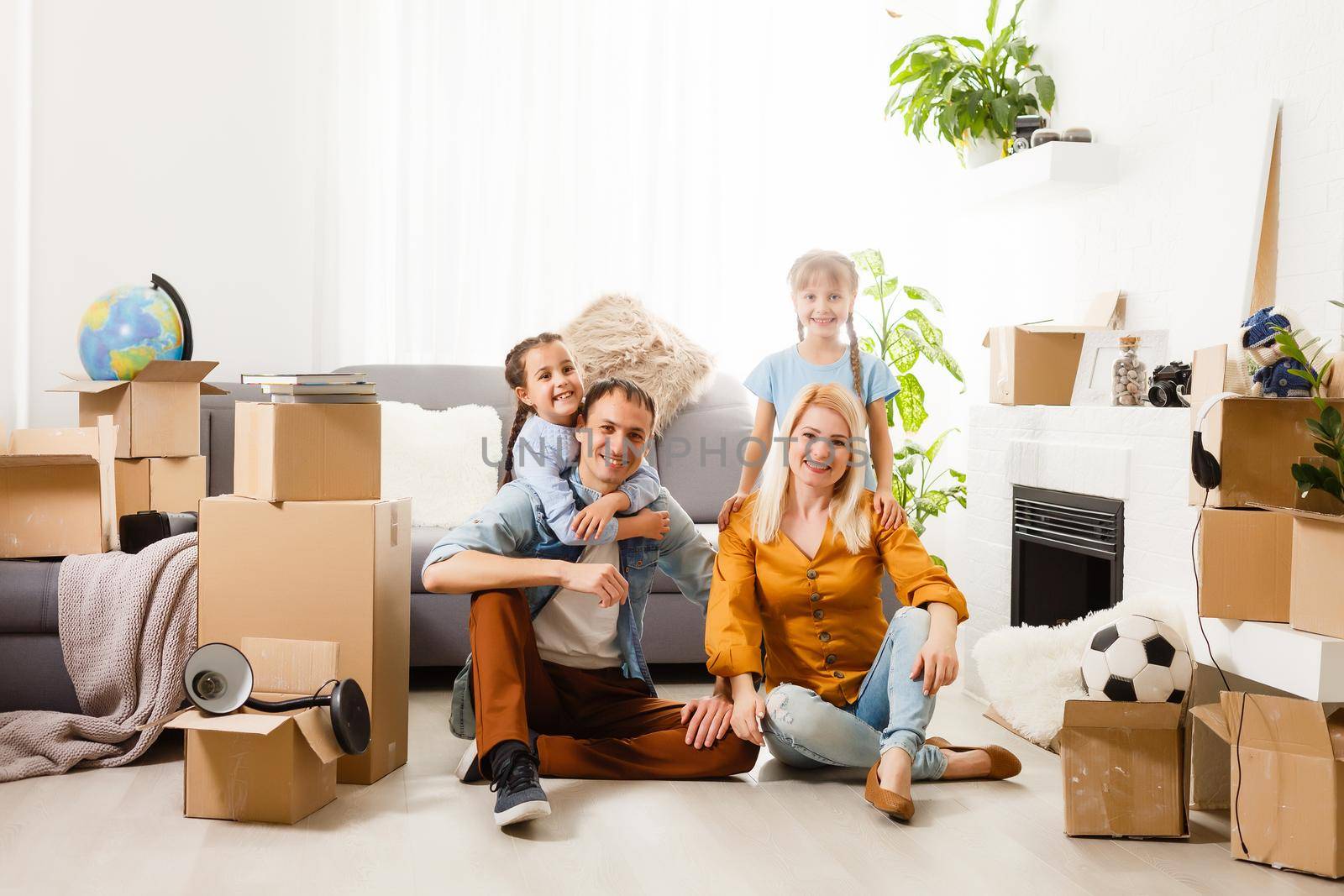 Happy family with cardboard boxes in new house at moving day. by Andelov13