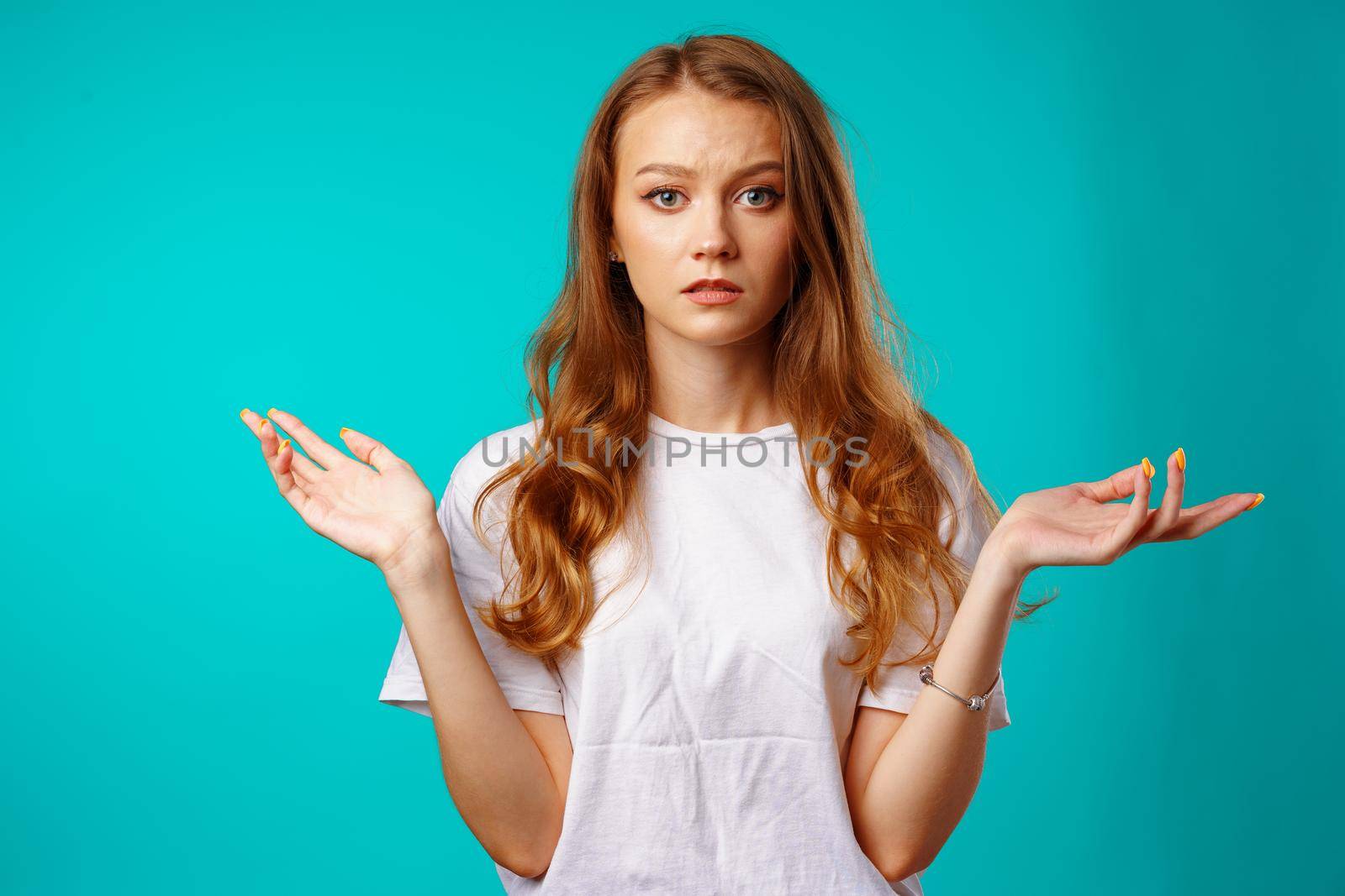 Young caucasian girl making do not know sign against blue background.