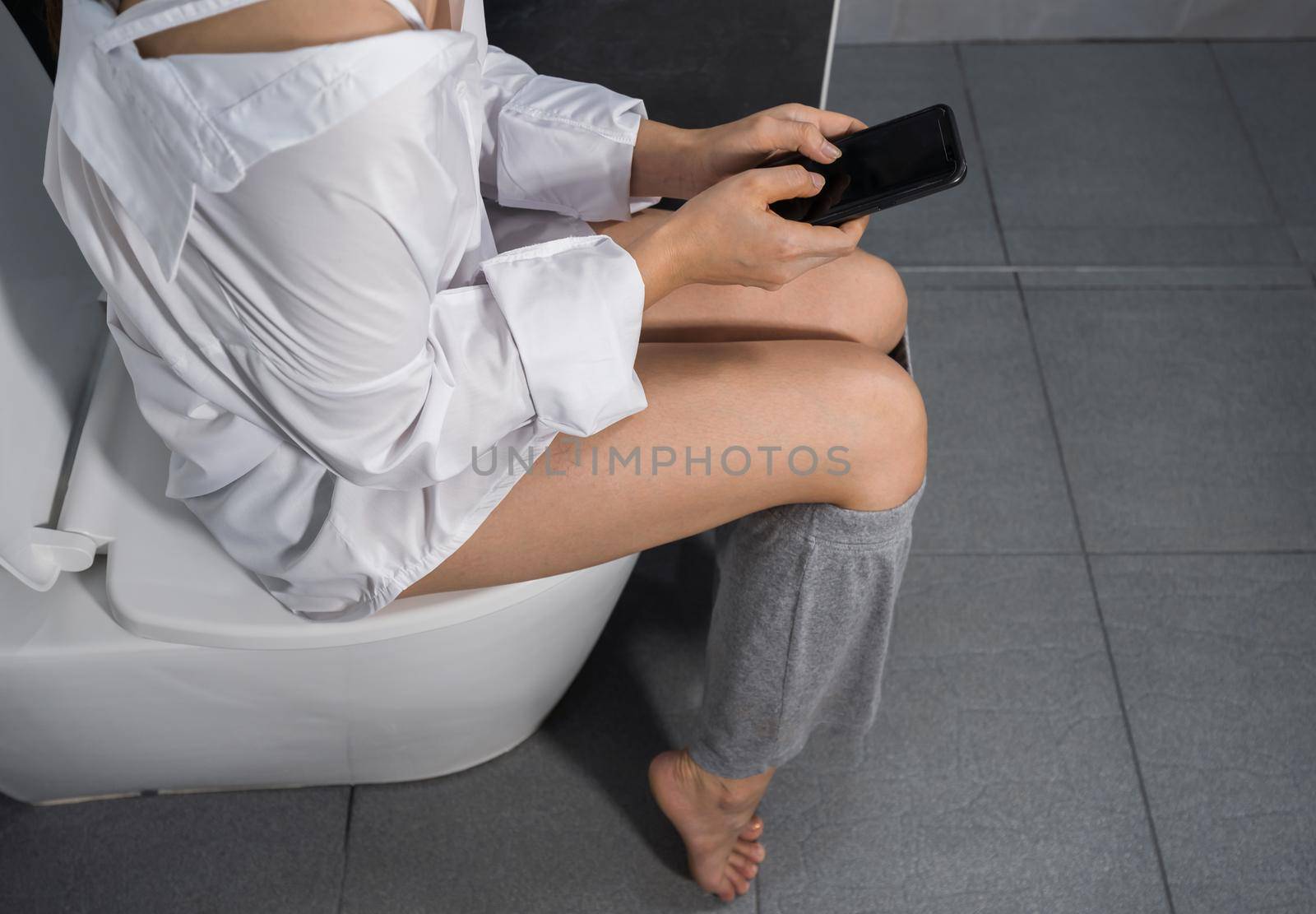 woman using mobile phone and sitting on toilet  by geargodz