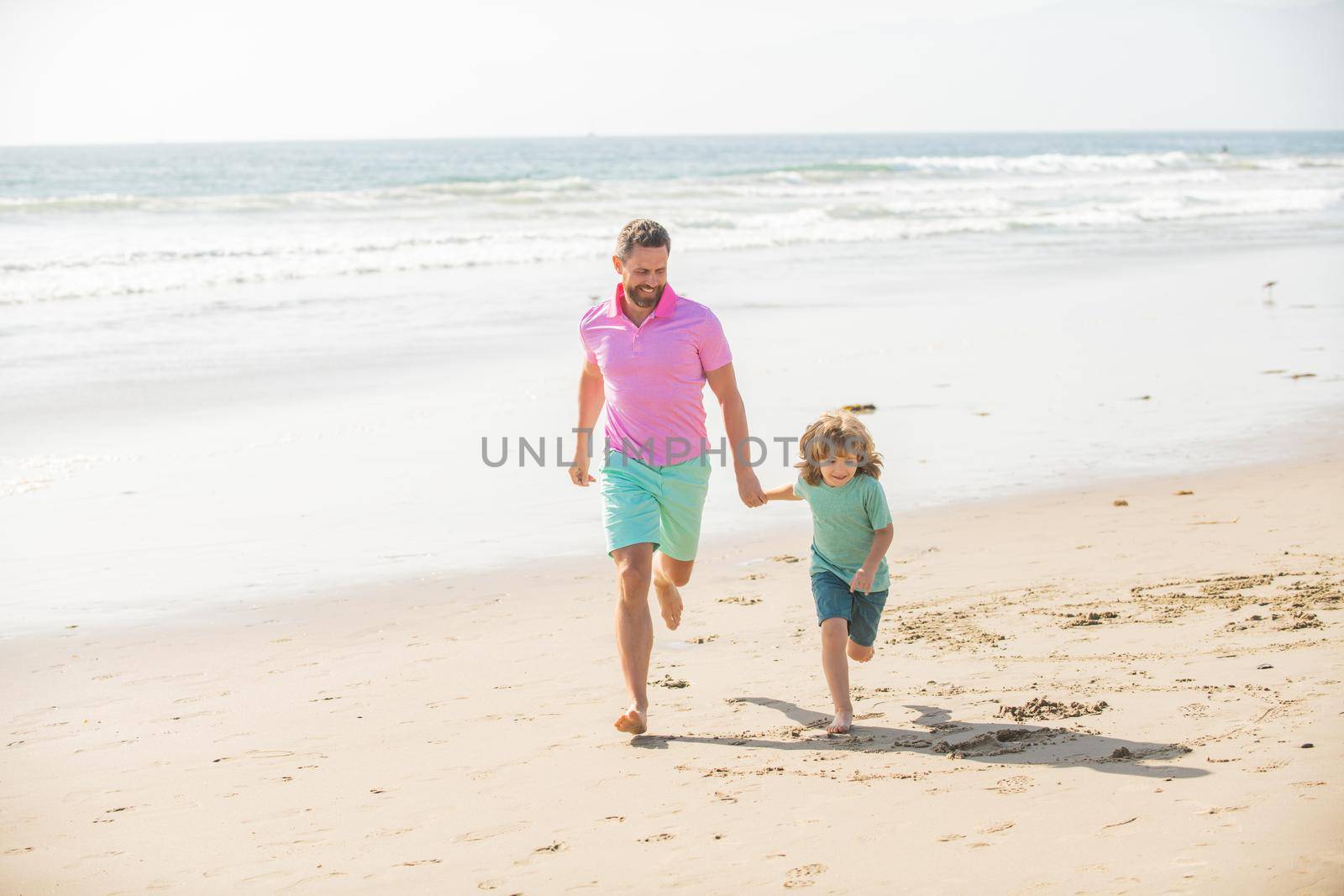 father and son run on summer beach, lifestyle.