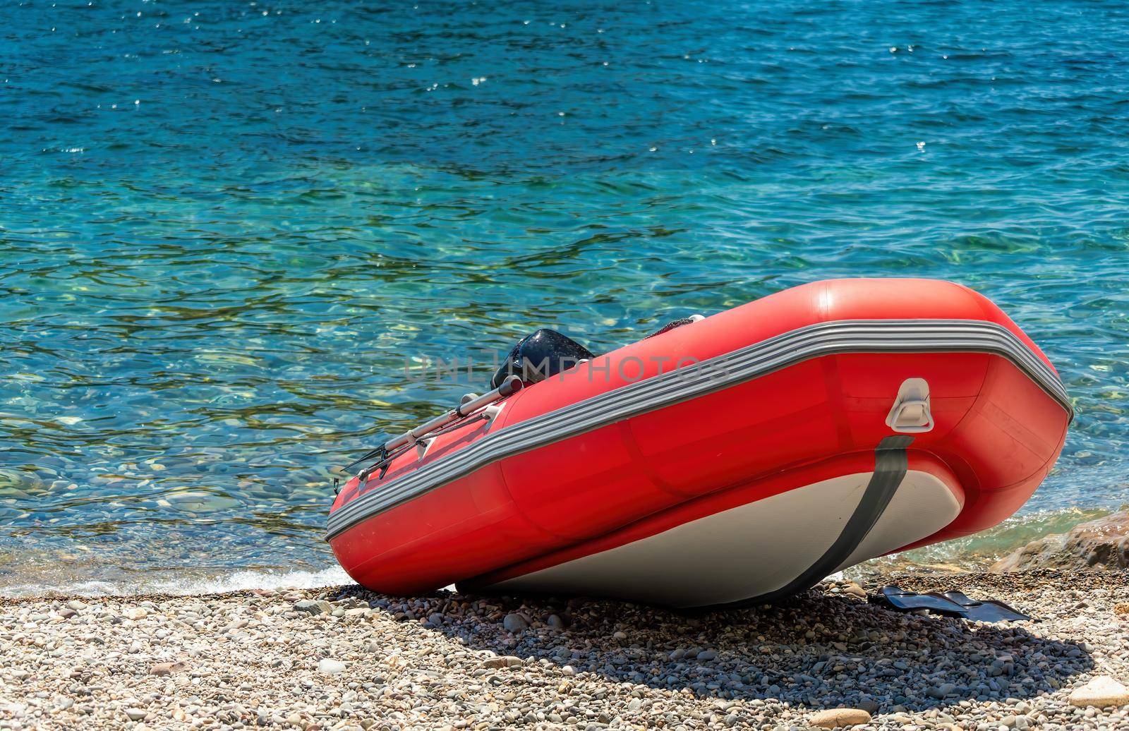 Red rescue inflatable boat, closeup. Empty marine rescue boat. Inflatable boat on the beach it is red in colour with a grey floor and black stripes