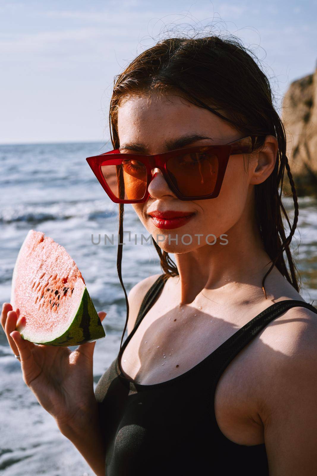 woman in black swimsuit with watermelon by the ocean. High quality photo