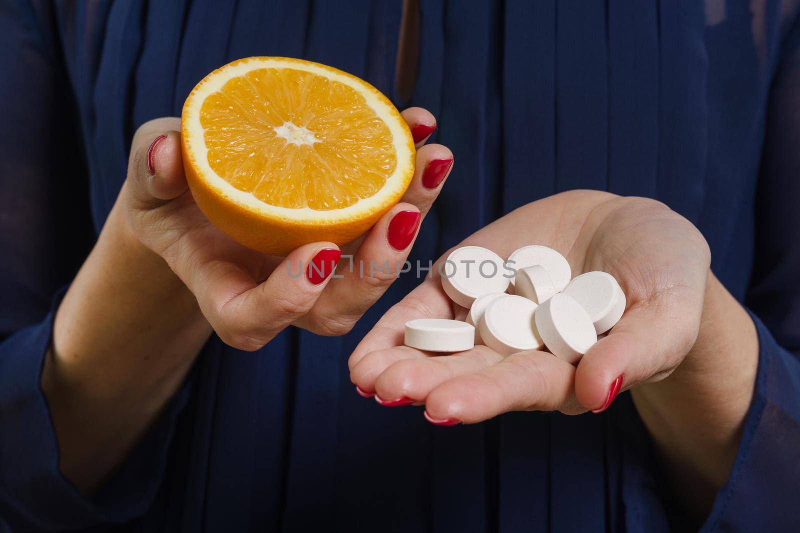 A woman holds a natural vitamin-orange in one hand and a synthetic vitamin C in the other. Makes a choice