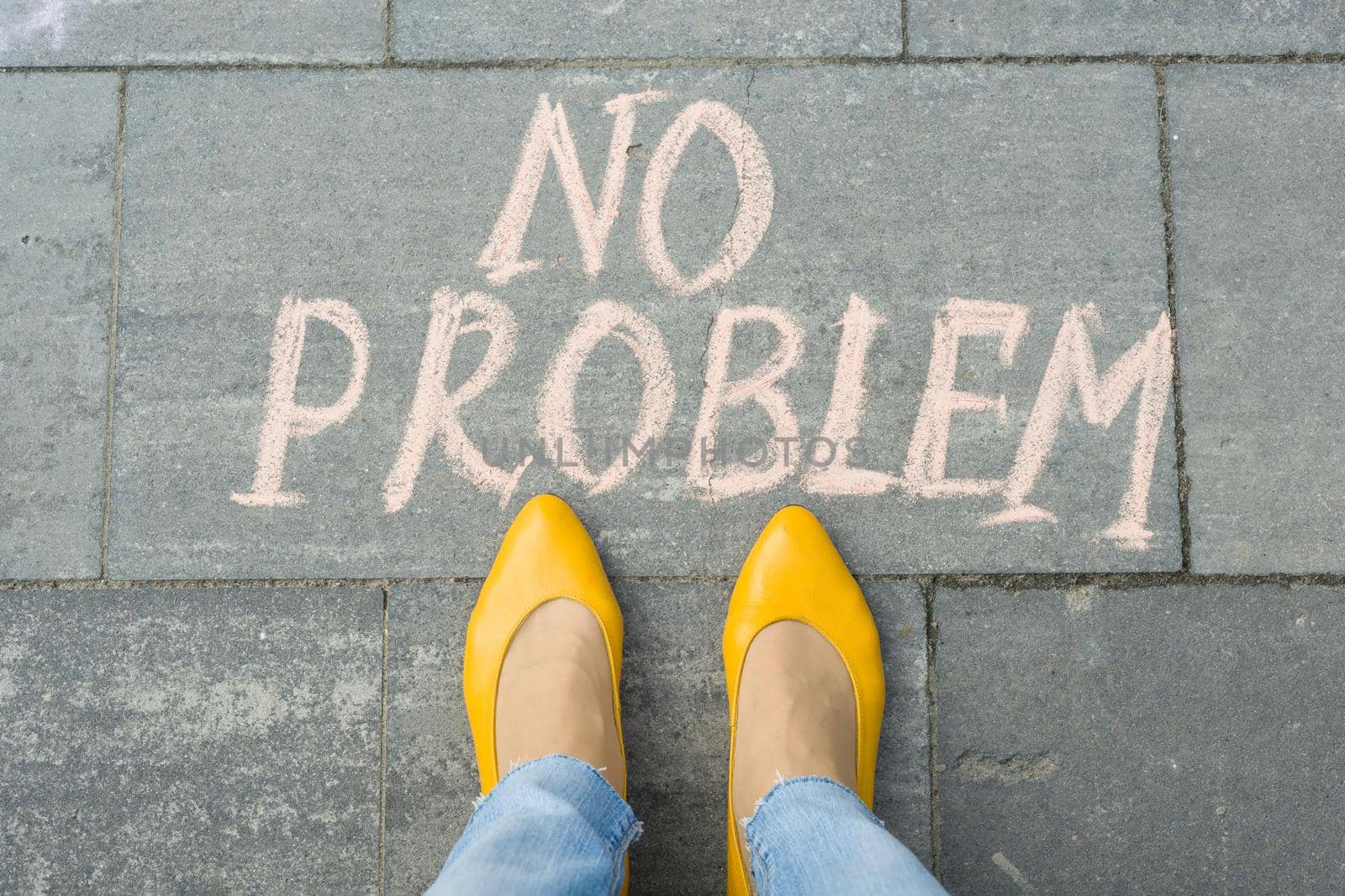 Female feet with text no problem written on grey sidewalk.