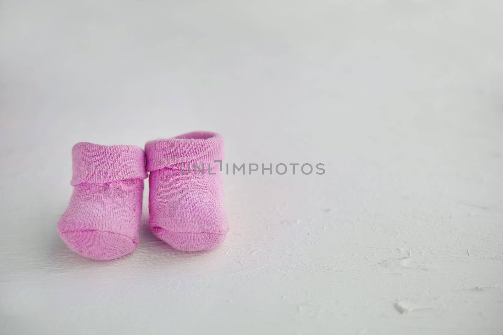 Pink baby socks on a textured rustic background with copy space. Newborn and pregnancy concept. Little girl socks